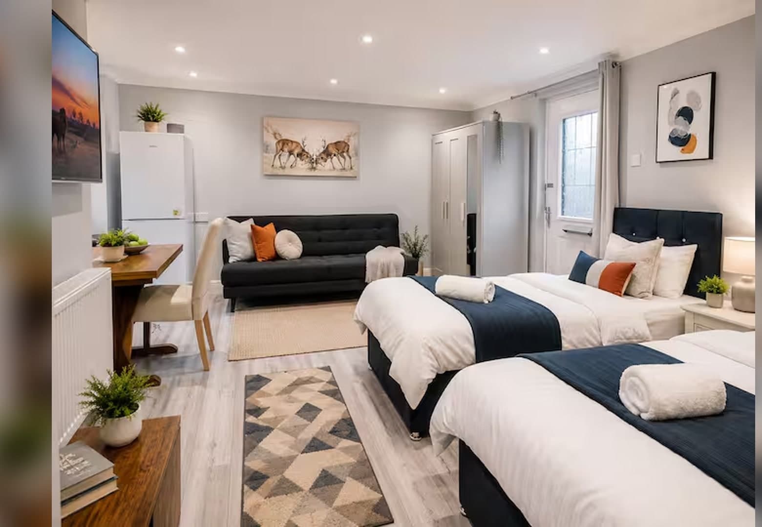 Full view of the studio — twin beds, sofa and workspace